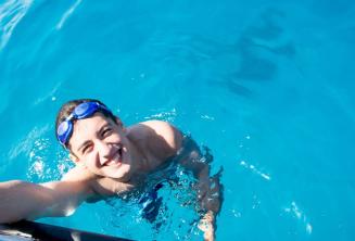 Študent plávajúci vedľa lode v Comine.