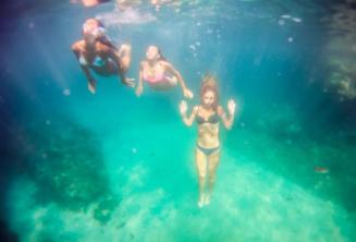 3 priatelia plávajúci pod vodou.